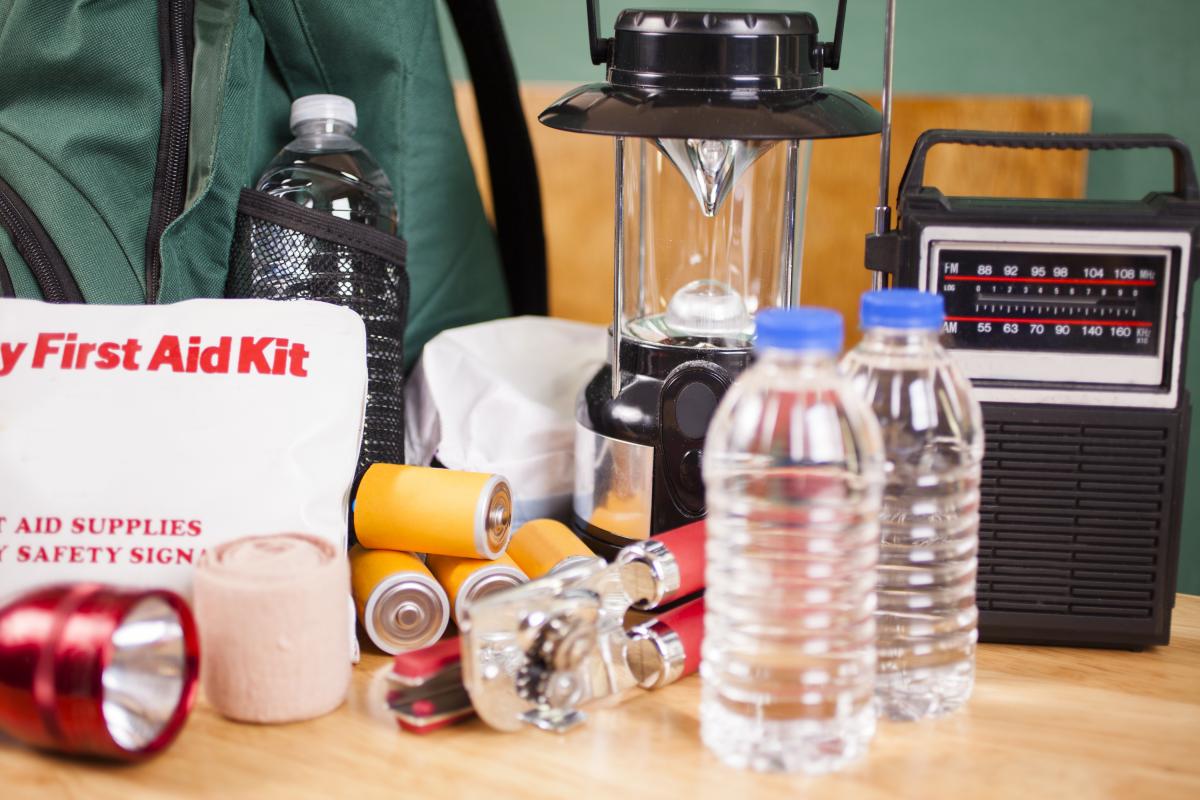 Photograph of emergency preparedness items - first add kit, bottled water, can opener, batteries, flashlight, weather radio